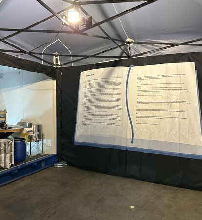 The interior of a 6x4 m folding gazebo can be seen. You can see its aluminium structure, the LED spotlights, the weights on the floor and the printed side wall. 