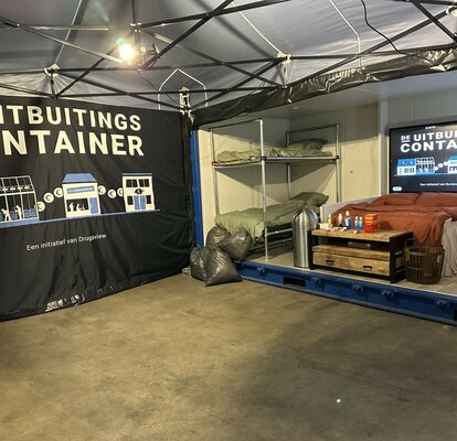 You can see the inside of a 6x4 m folding gazebo. You can see its aluminium structure, the LED spotlights, the printed side wall and the beds in the container next to it. 