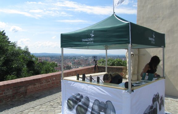 Zwei Mitarbeiterinnen der Firma Swarovski Optik nützen die Theke des Faltpavillons, um Ferngläser und Broschüren zu verteilen.