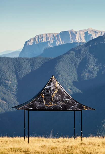 Schwarzes Faltzelt mit 4 Vordächern und individueller Bedruckung auf dem Plose-Berg. Dahinter erstreckt sich die Bergkette.