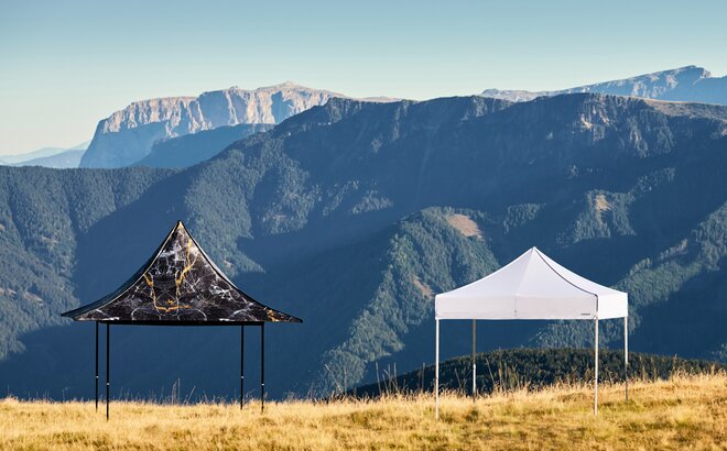2 gazebos of the quality series S1 and S2 stand side by side on the Plose mountain. One folding tent is printed, the other is classic white. 