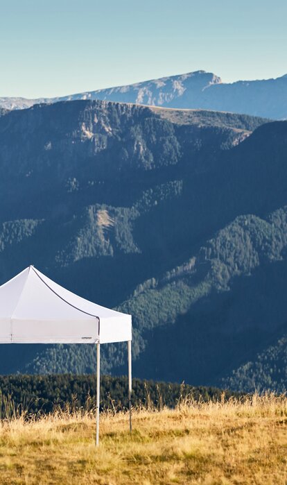 Gazebo pieghevole bianco sulla montagna Plose. Dietro si vedono le catene montuose.