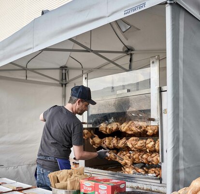 Cuoco cucina lo spiedo ad un evento sotto un gazebo cucina refrattario e ignifugo Mastertent