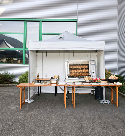Spit-roasted chicken cooked under a Mastertent fireproof kitchen gazebo at an event 