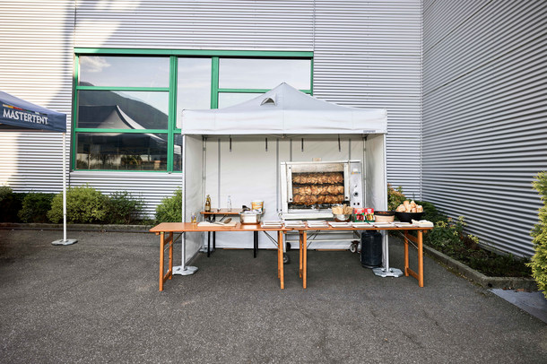 Spit-roasted chicken cooked under a Mastertent fireproof kitchen gazebo at an event 