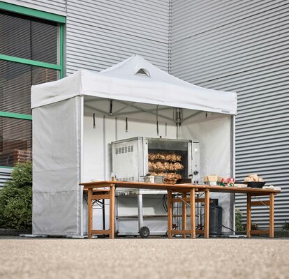 Spit-roasted chicken cooked under a Mastertent fireproof kitchen gazebo at an event 