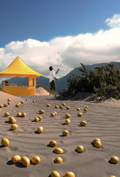 Gelber Faltpavillon der Größe 3x3 m mit Vordach und verschiedenen Seitenwänden auf sandigem Untergrund inmitten der Wüste. Ein Mann jongliert neben dem Faltzelt.