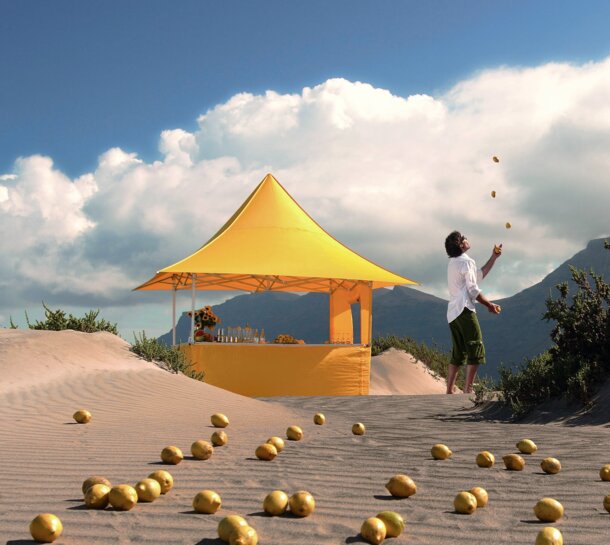 Yellow gazebo of the size 3x3 m with awning and various sidewalls on a sandy ground in the middle of the desert. A man is juggling next to the gazebo.  