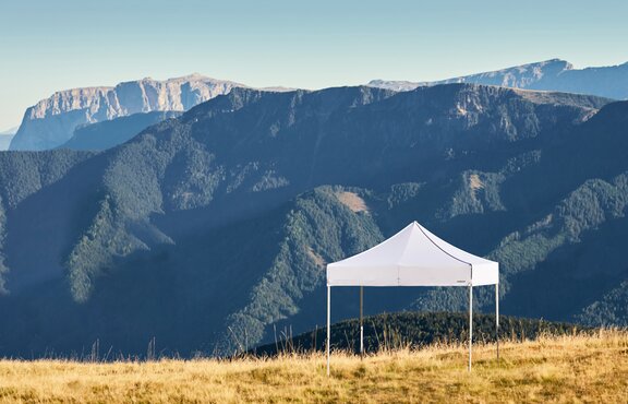 Weißer Faltpavillon auf dem Plose-Berg. Dahinter sieht man die Bergkette.