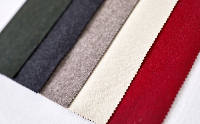The five fabrics of the loden tent are lying next to each other: green, dark grey, light grey, beige, red. 