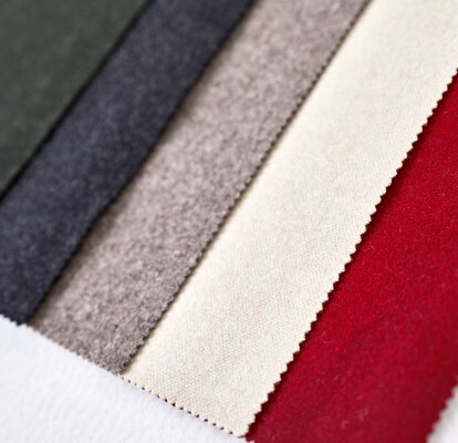 The five fabrics of the loden tent are lying next to each other: green, dark grey, light grey, beige, red. 