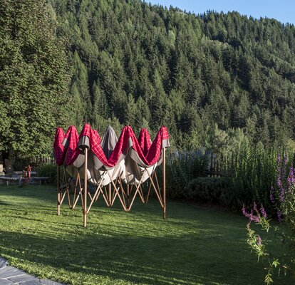 Half-opened gazebo with red-grey loden fabric cover in the garden. 