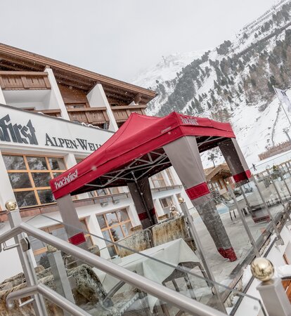 Gazebo esterno Mastertent 3x3m con copertura Loden per entrata hotel di montagna di lusso in inverno con la neve. Colori alpini marrone e rosso. Atmosfera montana e natalizia.