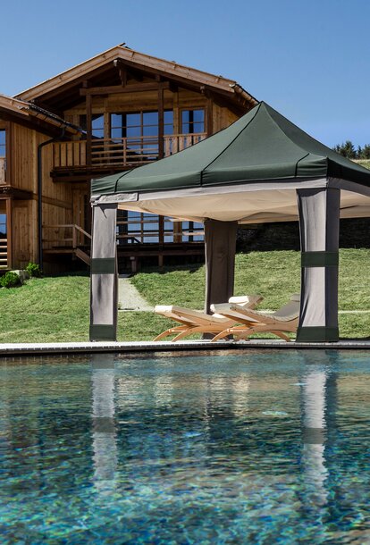 Next to the swimming pool there is a Loden gazebo with heaven - a loden ceiling attached under the roof. Under the loden tent there are two deckchairs. 