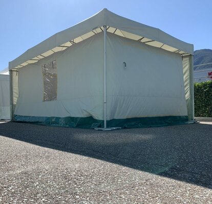 Ein Faltpavillon mit Thermozelt steht an einem heißen Sommertag auf einem Platz. 