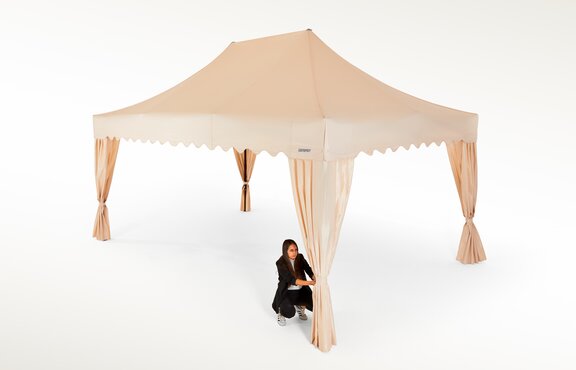 Die Frau bringt die Eckvorhänge beim Faltpavillon in ecru in Ordnung.