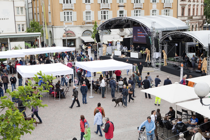 Many white custom-made gazebos with flat roofs at a festival. 