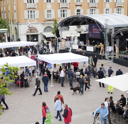 Many white custom-made gazebos with flat roofs at a festival. 