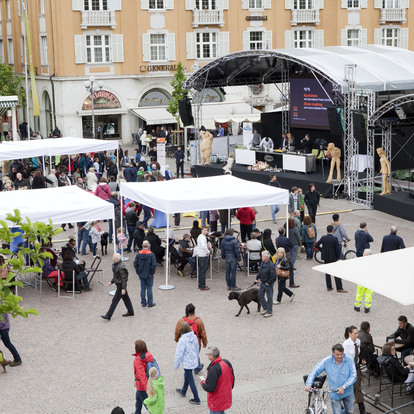 Many white custom-made gazebos with flat roofs at a festival. 