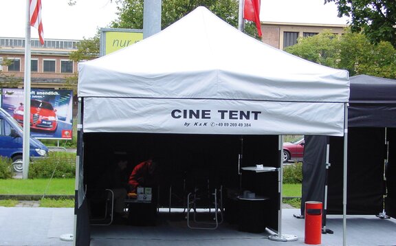 Der speziell angefertigte Faltpavillon ist mit einem abnehmbaren "CINE TENT"-bedrucktem Werbebanner ausgestattet. Dieser wird mit einem Klett wie eine Seitenwand am Dach und an den Eckstehern des Faltpavillons befestigt.