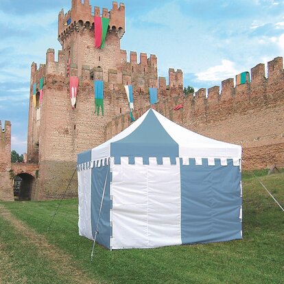 Składany na zamówienie namiot w kolorach niebieskim i białym stoi na łące przed zamkiem. Rozkładany pawilon posiada parawan z zamkiem.