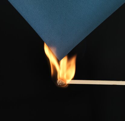 A burning match is used to ignite the blue fabric of the gazebo. 