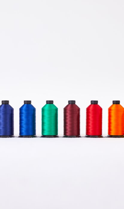 All thread rolls for the fabric colours of the gazebos are presented next to each other. From black to white.