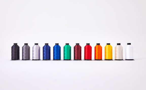 Tutti i rotoli di fili per i diversi colori di stoffa sono uno di finaco all´altro. Dal nero al bianco.