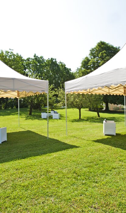 Gazebo pieghevoli color crema con tetto a pagoda con frontalino ondulato in un giardino per lounge evento all'aperto