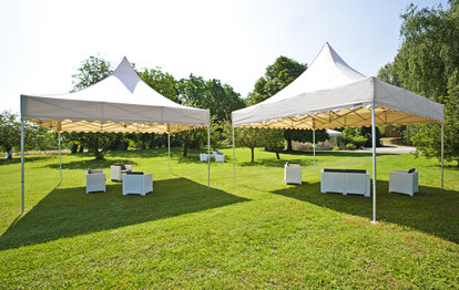Pavilioane pliabile crem cu acoperiș pagodă și fustă ondulată într-o grădină pentru eveniment lounge în aer liber