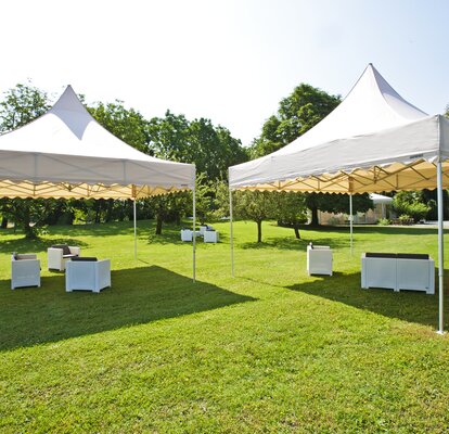 Gazebo pieghevoli color crema con tetto a pagoda con frontalino ondulato in un giardino per lounge evento all'aperto