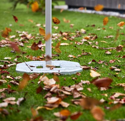 Il gazebo pieghevole è fissato con dei pesi. Il vento soffia tra le foglie.