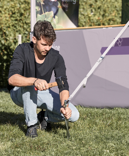 Fijación de la carpa plegable en un prado con tensores de seguridad y piquetas.