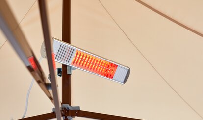 A mobile infrared heater mounted on the mast of a Mastertent canopy tent.