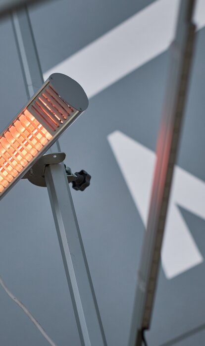 A mobile infrared heater mounted on the mast of a Mastertent canopy tent.