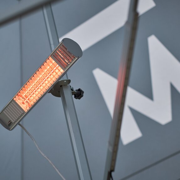 A mobile infrared heater mounted on the mast of a Mastertent canopy tent.