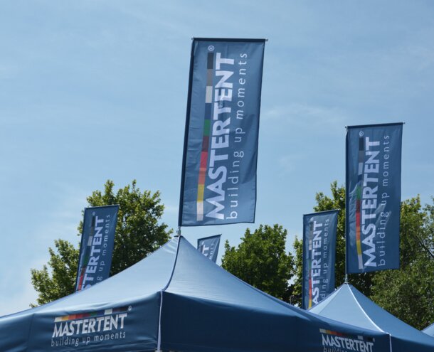 Blaue Faltzelte haben auf der Dachspitze eine Fahne mit der Aufschrift MASTERTENT.