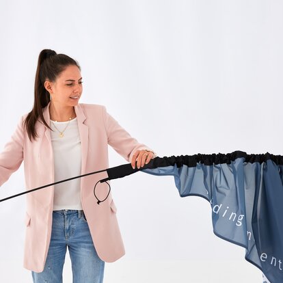 A woman is assembling the MASTERTENT beach flag. 