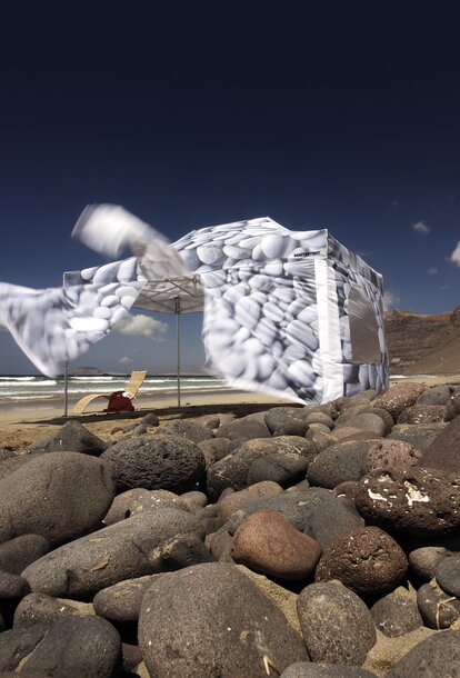 Bedruckter Faltpavillon mit Seitenwänden steht auf dem Strand von Fuerteventura. Der Wind bläst die Seitenwände in die Höhe.