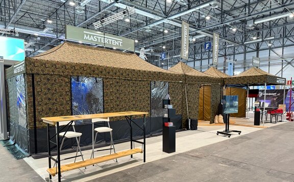 Military tents with camouflage patterns at a trade fair.